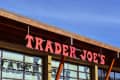 Trader Joe's storefront with red signage and wooden beams under a clear blue sky.