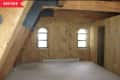 Empty attic room with wood-paneled walls, exposed beams, and two arched windows.