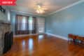 Empty living room with blue walls, wooden floor, stone fireplace, ceiling fan, and small wooden table by the door.