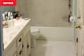 Bathroom with a white vanity, hexagonal tile floor, and a shower curtain covering the bathtub. Various toiletries are on the counter.