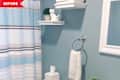 Bathroom with blue striped shower curtain, white shelves, decorative cat, tissue box, and towel on ring.