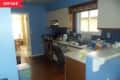 Cluttered kitchen with blue walls, dark wood cabinets, and a view into a dining area.