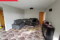 Living room with gray sectional sofa, patterned carpet, dark cabinet with toy cars, and a "Before" label in the corner.