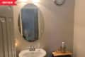 Before: tan bathroom with oval mirror and builder-grade fixtures