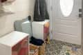 Before: entryway with baskets on the floor, low cabinets, and hanging hooks