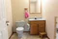 Before: Bathroom with tan vinyl floor, tan walls, oak vanity, and blue toilet