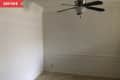 Before: A plain dining nook with a black ceiling fan, white walls, and tan floors
