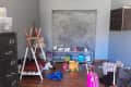 Before: Play room with toys on floor, dusty chalkboard wall, and black filing cabinet