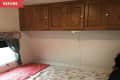 Before: Bed with floral quilt beneath brown wooden cabinets