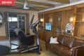 Before: Living room with wood-paneled shelving, exercise bike, and mustard-colored floors