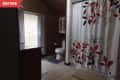 Before: Dark bathroom with tan floors, wood-paneled walls, and white floral shower curtain