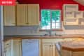 Before: Kitchen with red walls, pale yellow cabinets, and basic white square tile backsplash