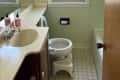Before: Bathroom with pale green walls and dated vanity and door