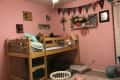 Before: Kids' bedroom with lofted bed, pink walls, and garland