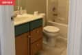Before: Bathroom with beige tile floors, beige walls, and a wood and green-painted vanity