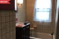 Before: Bathroom with white square tile and red paint on the walls, plus dark wood vanity