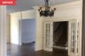 Before: Traditional dining room with brown wood floors and white walls, plus a black chandelier
