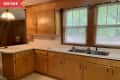 Before: 1970s-style kitchen with brown wood cabinets, beige vinyl floor, and off-white countertops
