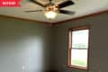 Before: Carpeted bedroom with green walls, brown trim, and dated ceiling fan