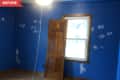 Empty room with blue walls, wooden door, window, and patches of white paint.