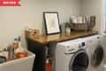 Before: beige laundry room with utility sink and wood counter over the washer and dryer