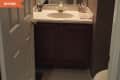 Small bathroom with dark wood vanity, white countertop, brass faucet, and decorative soap dispensers.