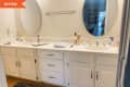 Double sink with oval mirrors and white cabinets