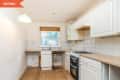 Small kitchen with white cabinets, wood countertops, gas stove, and a window with a wooden blind.