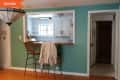 Kitchen pass-through with wooden counter, two wicker bar stools, teal walls, and a hanging stained glass light fixture.