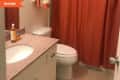 Bathroom with orange shower curtain, granite countertop, white sink, and toiletries on the counter.