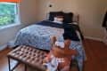 Bedroom with paisley-patterned bedding, brown tufted bench, and a plush toy wearing a Texas jersey.