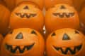 Stacked orange plastic jack-o'-lantern buckets with carved faces.