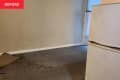Before photo of studio apartment area that will become the bedroom. Empty room with gray walls, dirty floor