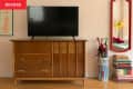 Before: Pink living room with a TV propped on a natural wood vintage sideboard in a medium brown tone.