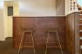 Two gold wire bar stools at a wooden counter near a staircase.