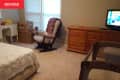 beige carpet, beige walls, beige rocking chair, wood dresser, white wood vanity, beige bedding, crib, tv