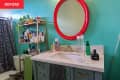 A teal bathroom with a red mirror over the sink