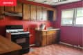 kitchen with red walls, wood cabinets, and reddish parquet flooring before renovation