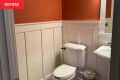 Cream wainscoting in orange painted bathroom before renovation.
