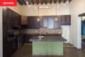 Dark brown wooden cabinets in kitchen with green island before renovation.