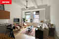 Wood sling chairs, glass coffee table, and neutral sofa in living room.