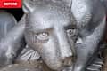 A close-up of a silver-painted sculpture of a panther's head, showcasing detailed fur texture and expressive eyes.