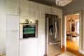 Stainless steel refrigerator in newly renovated kitchen with white cabinets.