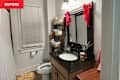 Small bathroom with a white shower curtain, dark granite sink, wooden mirror, and decorative red bows.