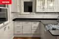 White kitchen cabinets with black granite countertops, marble backsplash, and a pendant light above the sink.
