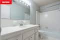 Bathroom with white tile walls, a large mirror, a sink with chrome fixtures, and a bathtub.