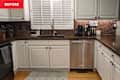 Dark countertops in kitchen with brown tile backsplash before renovation