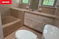 Bathroom featuring a beige bathtub, white toilet, and light pink hexagonal tile flooring.