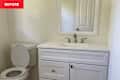 Bathroom with a white vanity, sink, and mirror, alongside a toilet in a neutral-colored space.
