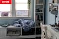 Cozy workspace with a blue chunky knit blanket on a shelf, books, and a desk with a laptop and lamp.